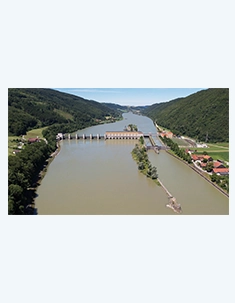 Ein Blick von oben auf das Kraftwerk Jochenstein an der Donau. Auf der rechten Seite sieht man eine kleine Ortschaft und die Schiffsschleuse.